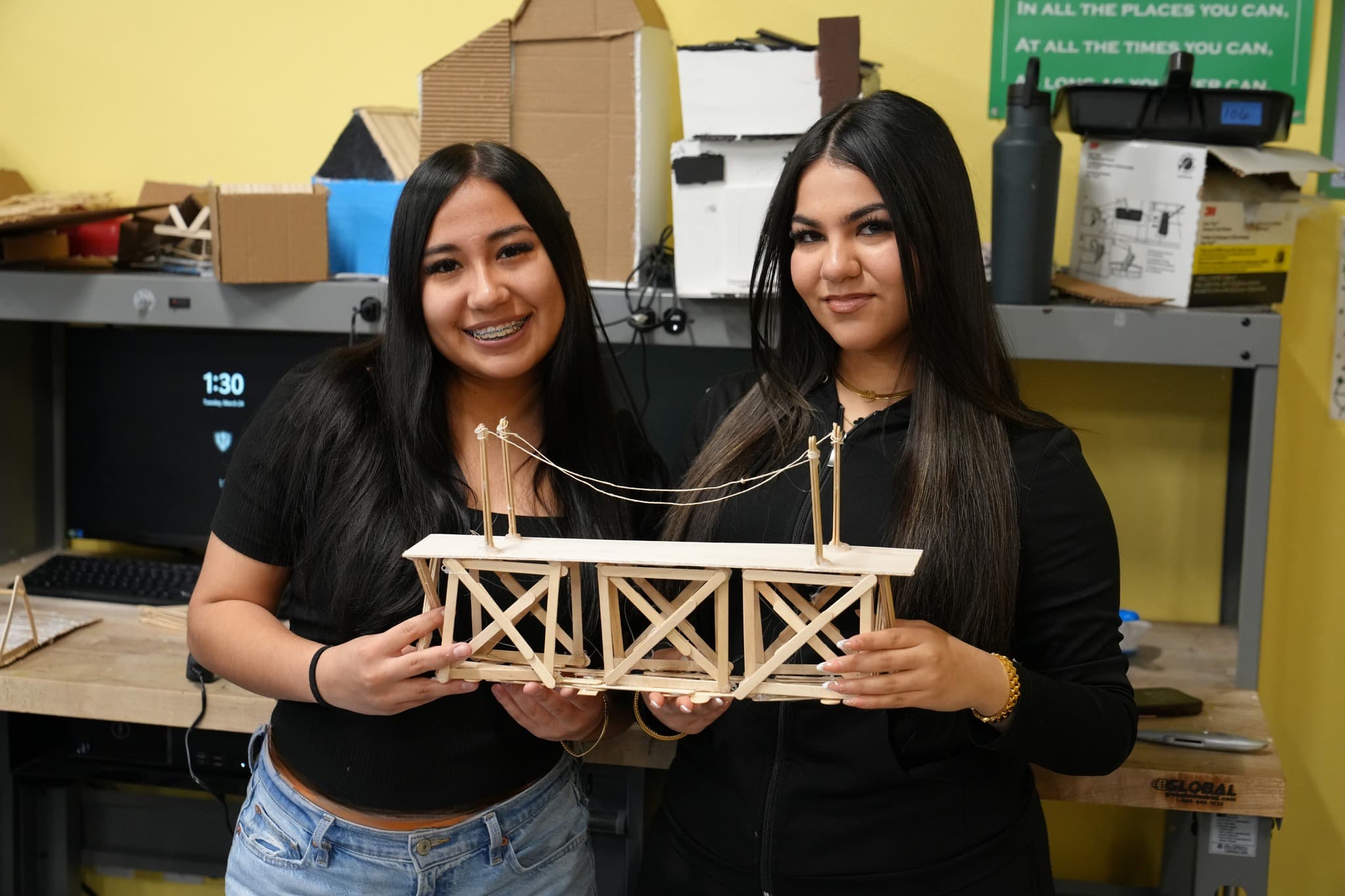 Highland Prep West students holding a truss bridge they designed and built